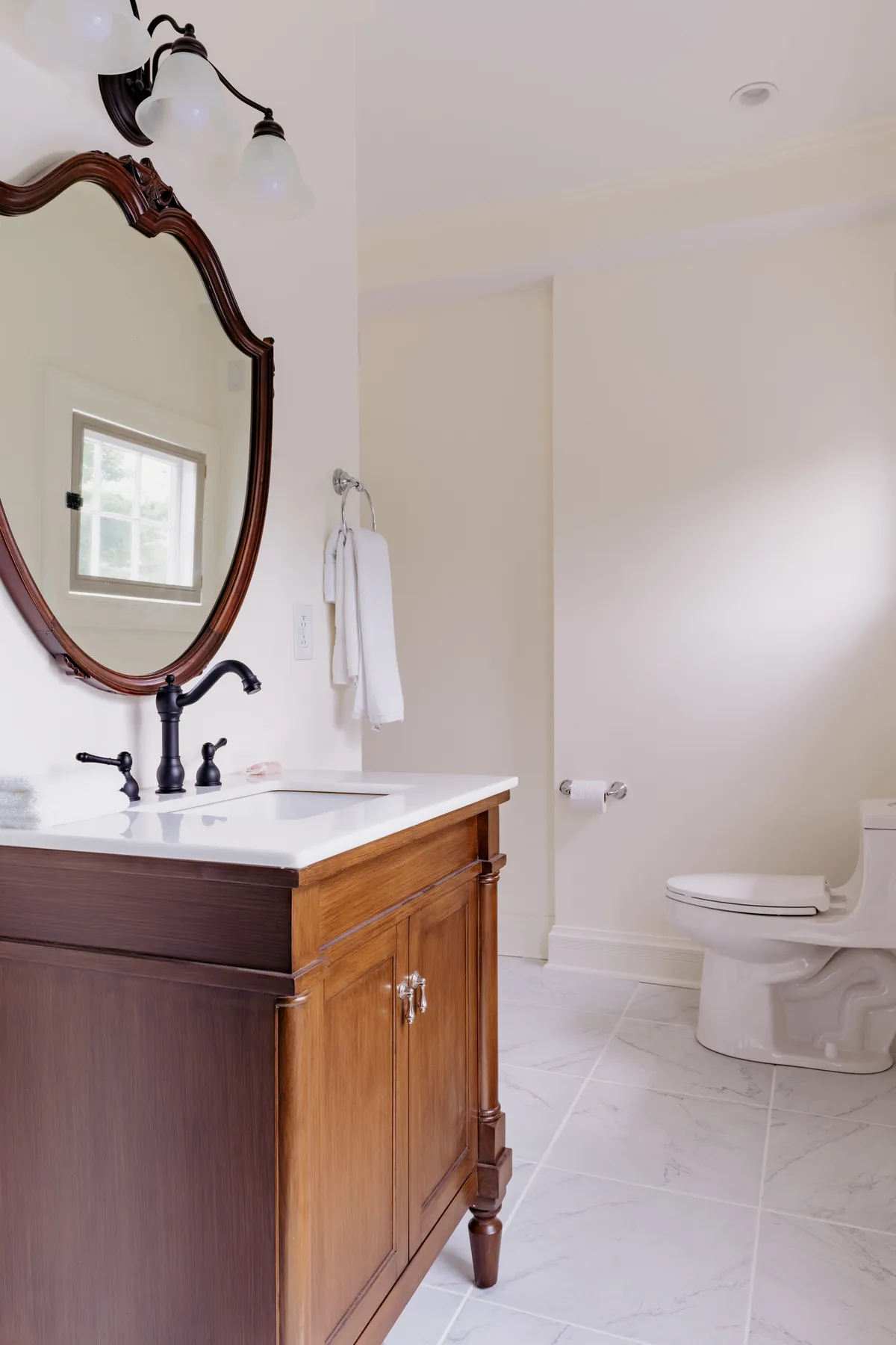 Dickens Suite bathroom vanity with arched mirror, dark bronze faucet and toilet
