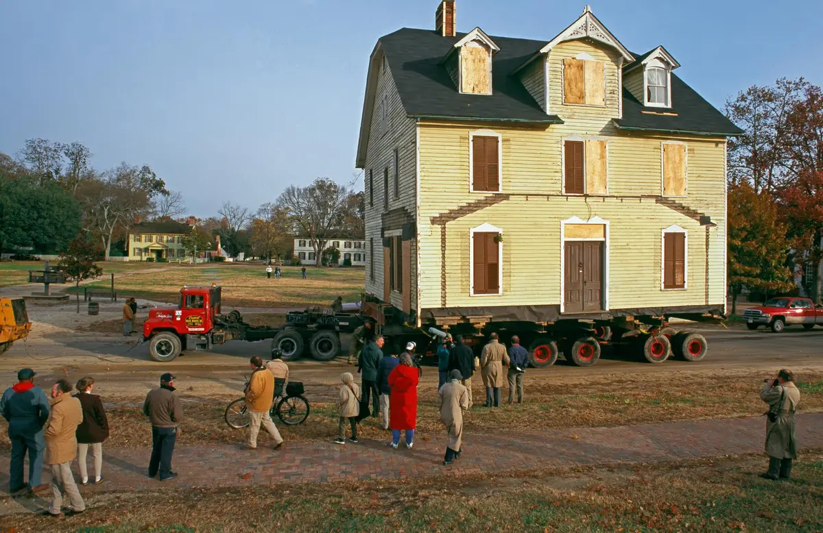 The Armistead House mounted on a flatbed transport vehicle during its 1995 relocation in Williamsburg, Virginia, as a crowd of onlookers watches from Duke of Gloucester Street